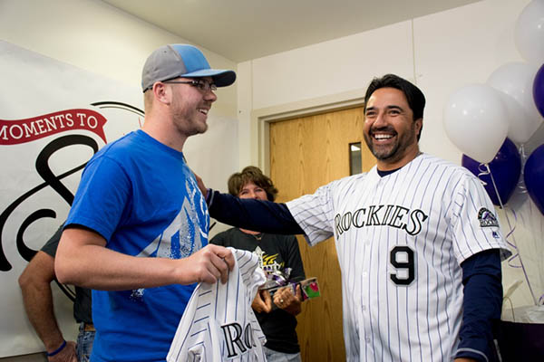 Jeb Schroder, a patient who coped with testicular cancer gets to meet former Colorado Rockies player, Vinny Castilla. Castilla is wearing his Rockies jersey and is handing one to Schroder.