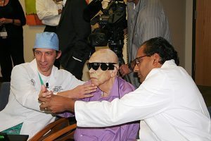 Two doctors help a patient look at his hand with a new bionic eye.
