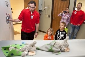 two elephant stuffed animals go through an x-ray machine while kids and parents watch