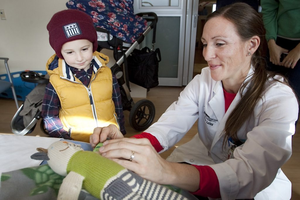 kids watches an ER doctor exam his bear's arm.