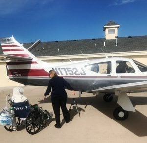 A nurse helps a patient board an airplane.