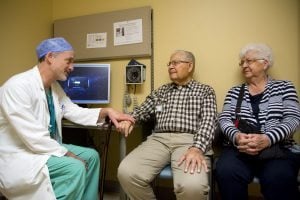 Dr. John Carroll talks with Don and Amy Lovell in a UCHealth University of Colorado Hospital exam room.