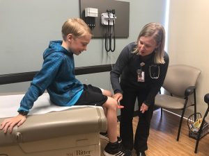Monica Lederman, PA-C, checks reflexes on a 9-year-old boy. Most Urgent Care locations are offering $30 sports and summer camp physicals.