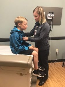 Monica Lederman, PA-C, checks the heartbeat of her son, Caleb, 9. UCHealth Urgent Care locations are currently offering $30 physicals for sports and summer camps.