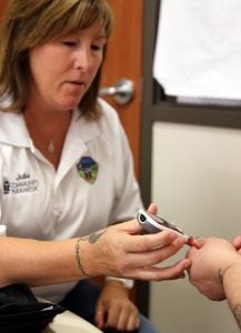 Julie Bower, paramedic for UCHealth EMS, tests a womens blood sugar level during EMS weekly clinic at the Larimer County Community Corrections.