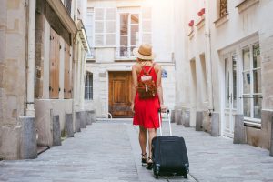 A photo of a woman pulling a suitcase down a street.