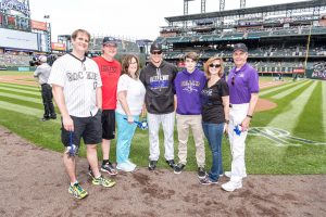 Volunteer Bob Allen and his family are shown on the field at Coors Field before a Colorado Rockies baseball game.