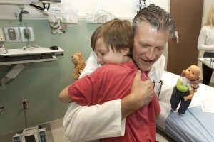 Doctor Jamie Teumer hugs a child named Owen Sykes after caring for his sister's doll during the opening of UCHealth Longs Peak Hospital.