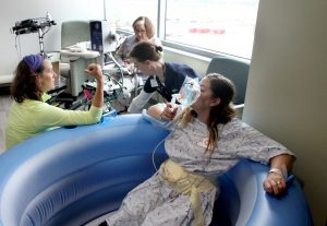 A woman breathes from a nitrous oxide mask while sitting in a water birth tub. She is surrounded by nurses who are helping her during a training before UCHealth's newest hospital opened in Longmont.