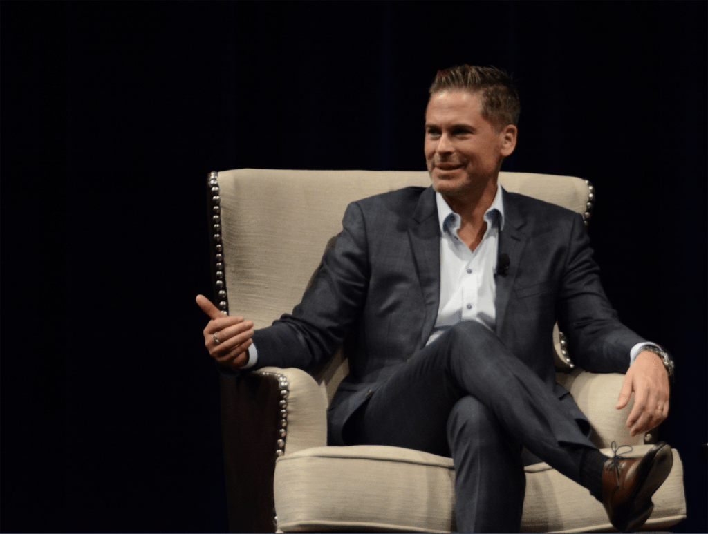 Actor Rob Lowe sits in a chair and speaks during an event to benefit CeDAR, a drug rehabilitation center.