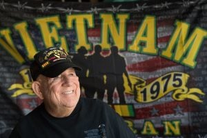 J.D. Hill at his home with a Vietnam Veteran flag behind him.