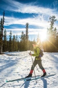 A cross-country skier glides across a snowy meadow.