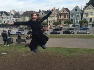 Becky jumping and smiling in a park.