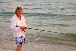 A man with a fishing pole on the beach.