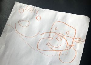 Natalie, who is 4, drew a picture of her dad before and after he needed a rescue in Australia. The picture in orange marker shows a person with a smiley face. On the right the same face has all kinds of tubes and medical equipment attached to it. The drawing shows sickness through the eyes of a child.