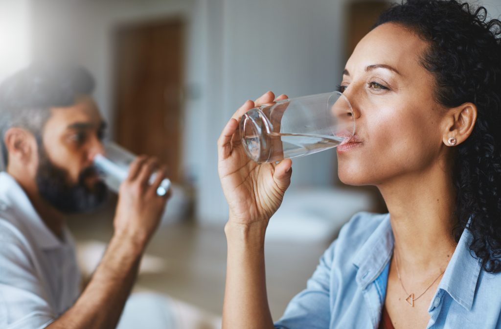 A photo of two people drinking water from glasses.