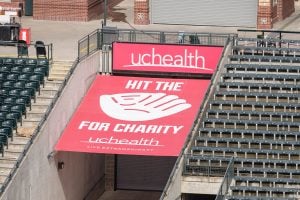 A red "Hit the Mitt" sign at Coors Field in Denver. The sign shows a big mitt with Hit the Mitt spelled out around it and UCHealth at the top. Each time a Rockies player hits a homer that strikes the sign this year, the Gold Crown Foundation will get $5,000.