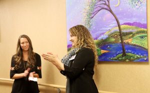 Anna Smoot, PVH and MCR Foundation development officer, right, introduces artist Tanielle Childres, left, and her painting, What a Wonderful World, at a recent event at UCHealth Medical Center of the Rockies. Its one of two paintings shes donated to UCHealth since losing her unborn child in 2012, and again in 2016.