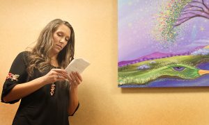 Artist Tanielle Childres explains what her painting, What a Wonderful World, symbolizes. The painting, which is created and donated to UCHealth Medical Center of the Rockies after her mischarge, now hangs in the hall of the Women and Family Unit.