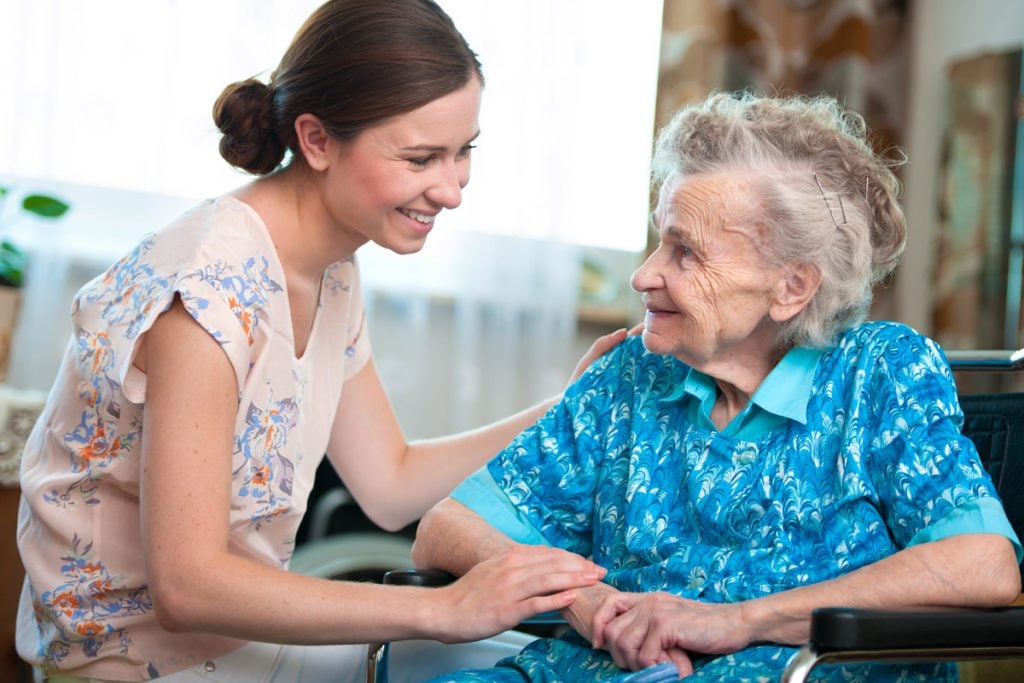 Elderly woman on wheelchair with a nurse