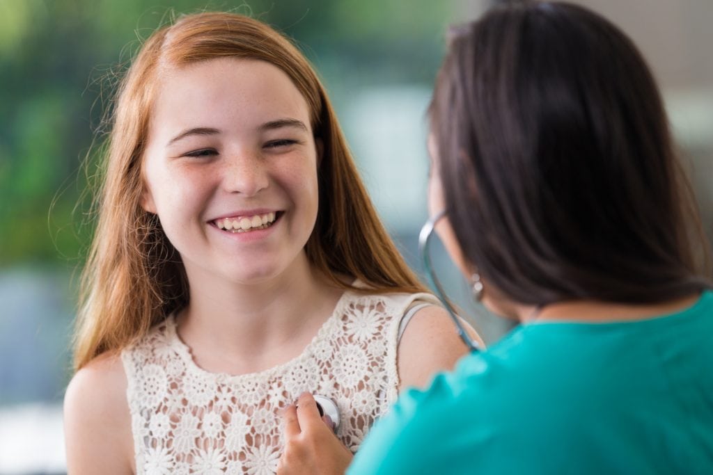 A preteen female patient is shown during a doctor's appointment.