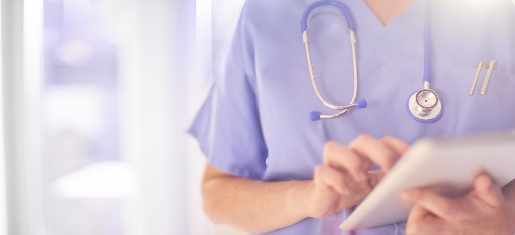 A nurse reviews an electronic medical record on a handheld tablet.