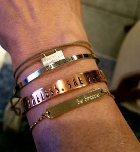 An arm with bracelets. They have positive messages like "be brave."