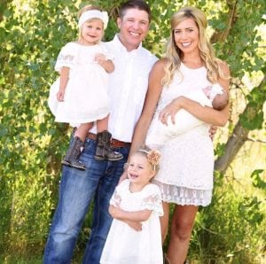 mom holds baby, standing next to day holding their second daughter and their oldest daughter standing in front.