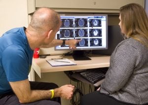 A doctor and a patient review MRI scans on a computer screen.