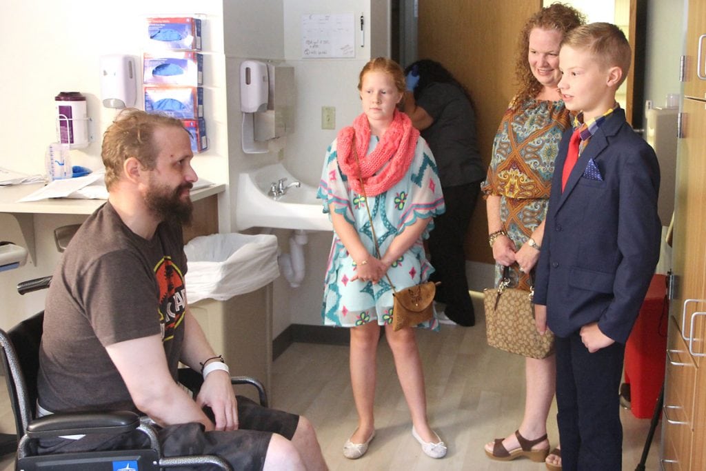 Charlie and his family talk with a patient in his room.
