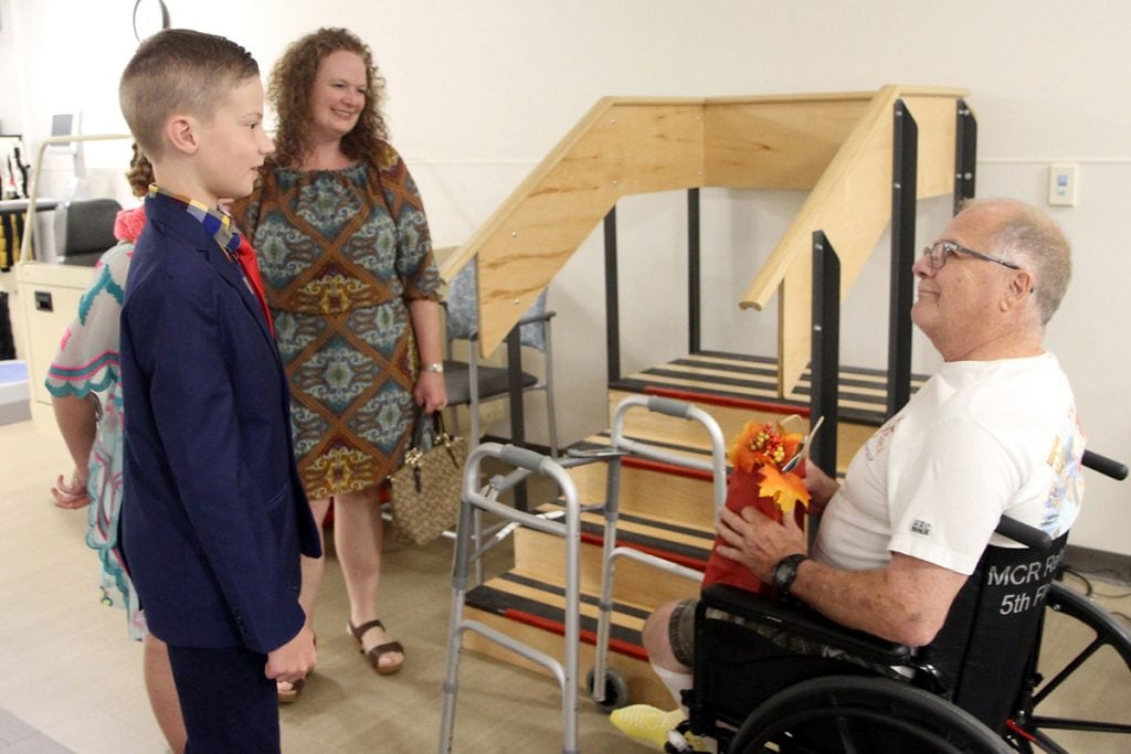 charlie and his family talk to a patient in the rehab gym.