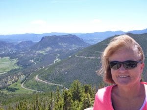 Trisha Washburn poses at the top of a mountain with a view behind her. She's coping with Alzheimer's and anxiety and is getting help through integrated care at her primary care clinic.