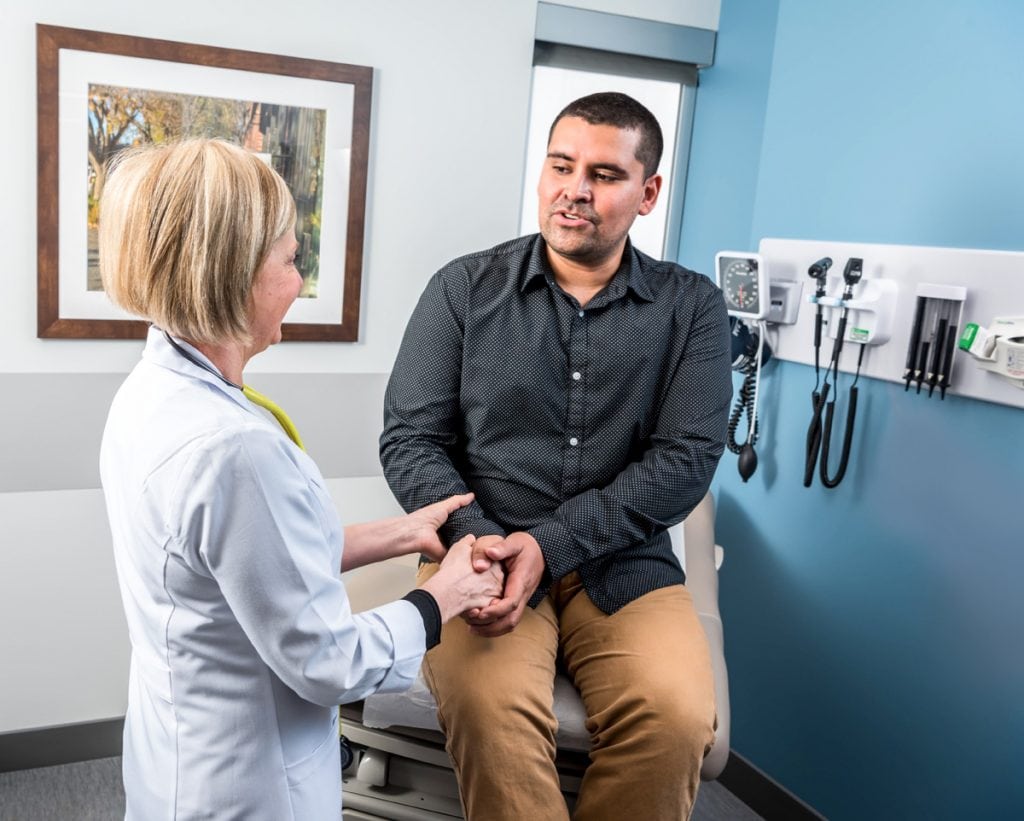 A doctor speaks with a patient in an exam room