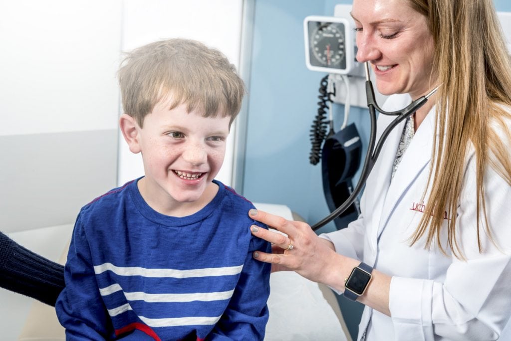 A doctor checks a young boy's lungs with a stethoscope.