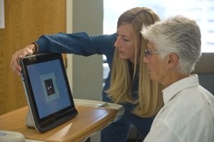 : Meghann Griffin, left, works with Arnette Schouten as they calibrate the Tobii Dynavox to recognize Schouten’s eye movements. Once calibrated the device uses two cameras below the screen to track eye movements that can enable typing and text-to-speech, web surfing and other activities familiar to computer users.