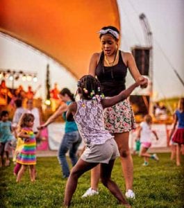 A young girl and a teen dance in the foreground at Central Park in Denver, one of our 14th best playgrounds in Colorado.