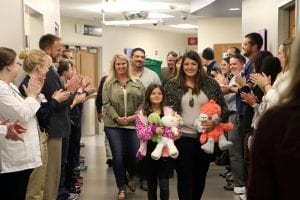 Marlie walking down hallway with family while UCHealth staff clap.
