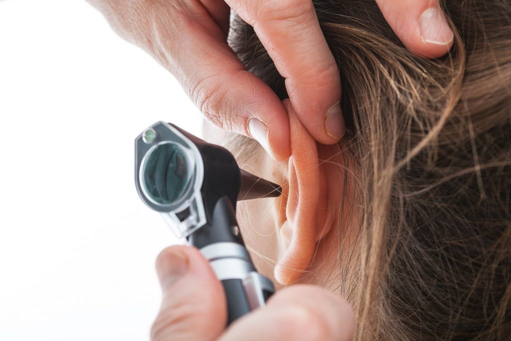 A person has their ear examined with an otoscope.
