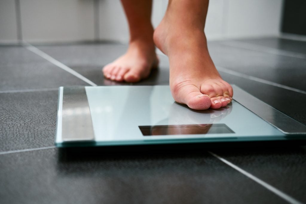 A woman with barefeet stepping on a scale.