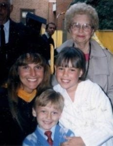 donna with her graduation gown and cap posing with two kids and mother