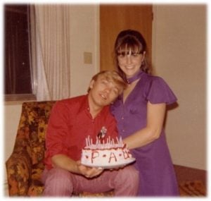 donna poses with paul, who is holding a birthday cake