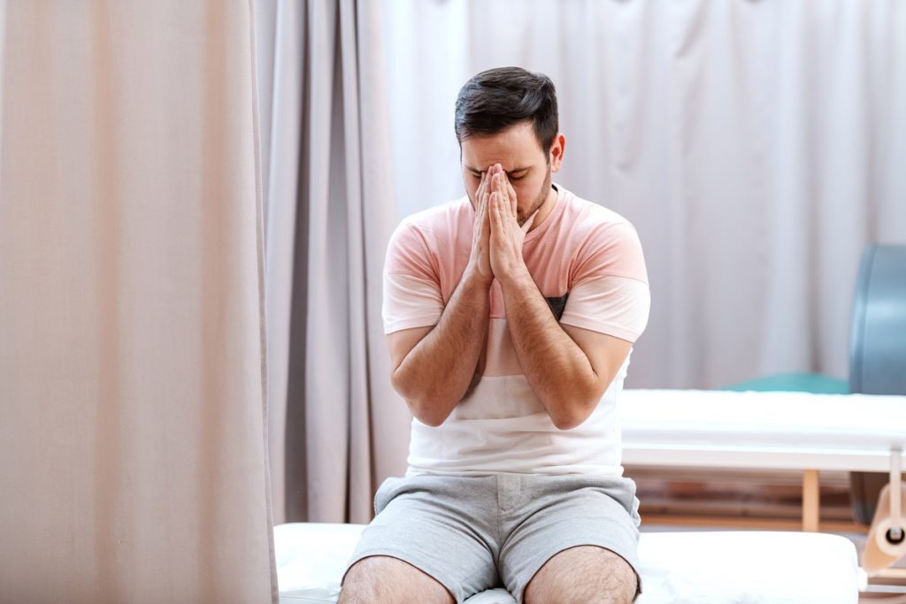 a man who is sick sits on a hospital bed in an ER