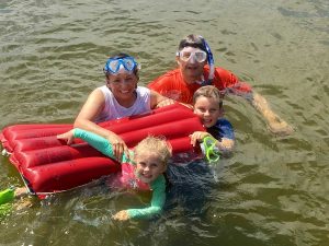 A photo of Lydia Friese in the water with her husband and grandchildren