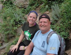 Image of Amy sitting next to her father during a break on a hike.