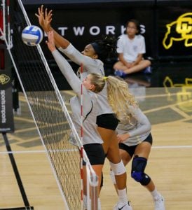 volleyball players blocking at the net, including Abu in a game after her meniscus surgery.