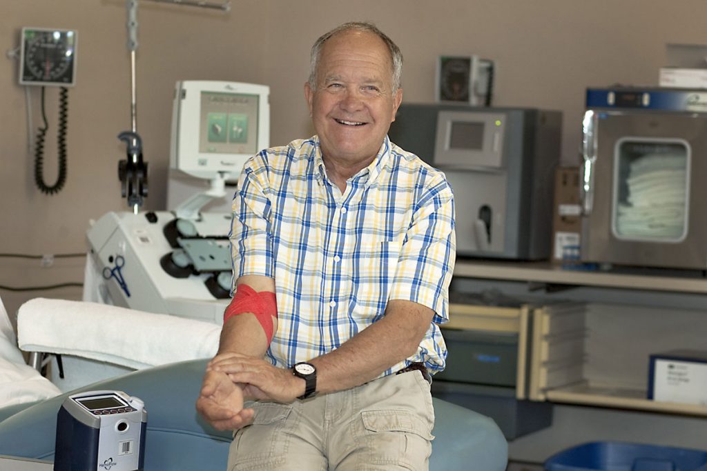 Simon with a red band around his arm after donating platelets for his 71st time.