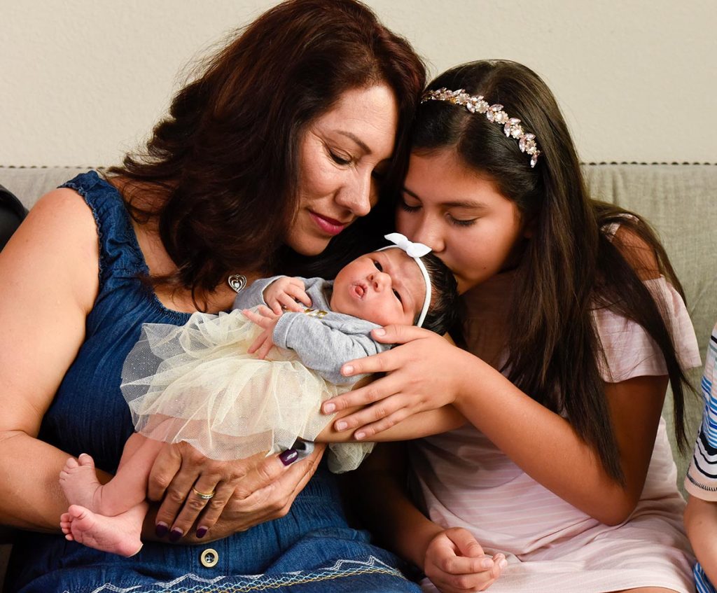 And grandmother holds her new granddaughter as her 10-year-old granddaughter kisses her new sister.
