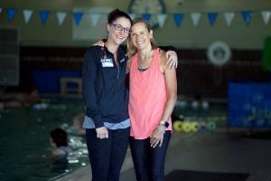 two women stand together by pool
