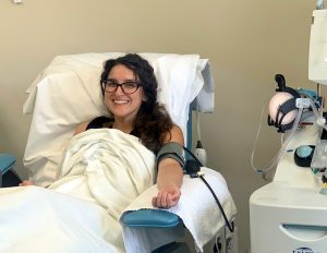 women smiles as she gives platelets at a blood donation center.