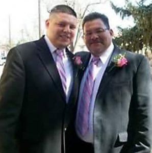 father and son in suits smiling.